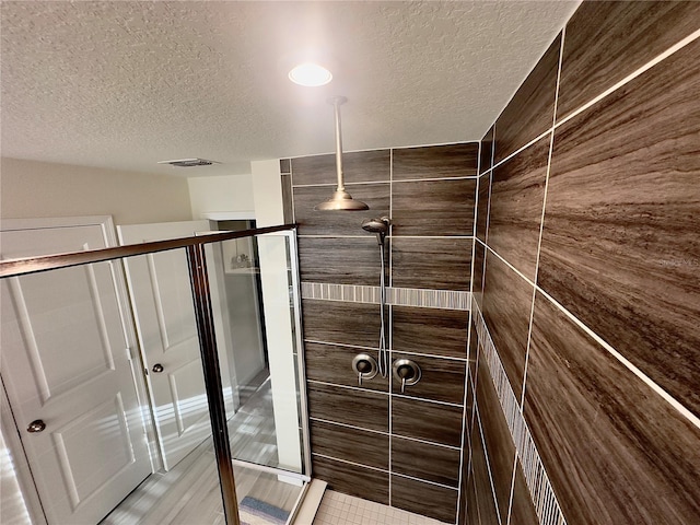 full bathroom with visible vents, a stall shower, and a textured ceiling