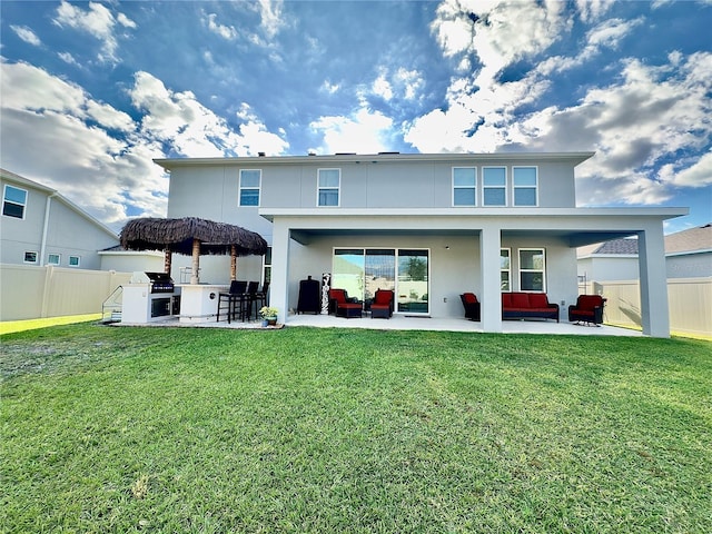 rear view of house featuring a patio, a yard, fence, and stucco siding