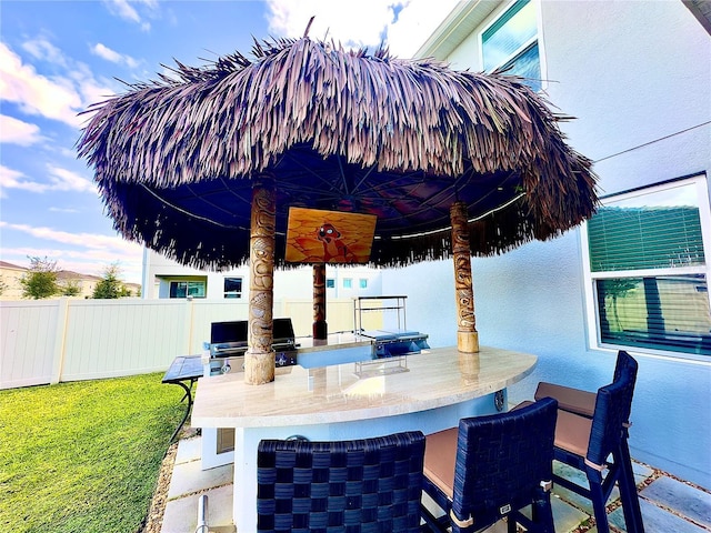 view of patio with outdoor wet bar, area for grilling, and fence