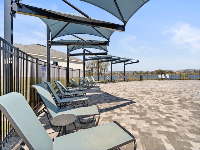 view of patio with fence and a water view