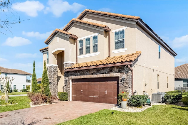 mediterranean / spanish-style home with central air condition unit, a garage, stone siding, decorative driveway, and stucco siding