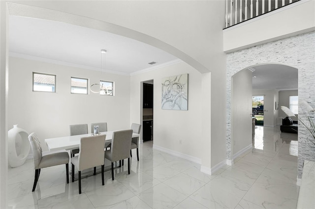 dining space with ornamental molding, arched walkways, marble finish floor, and baseboards