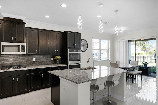 kitchen with decorative backsplash, appliances with stainless steel finishes, light stone countertops, crown molding, and a sink