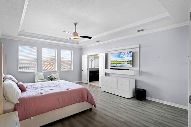 bedroom featuring wood finished floors, a raised ceiling, and baseboards