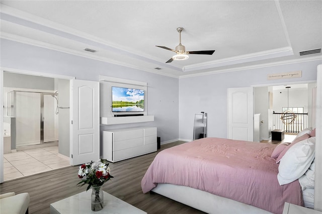 bedroom featuring a tray ceiling, visible vents, and crown molding