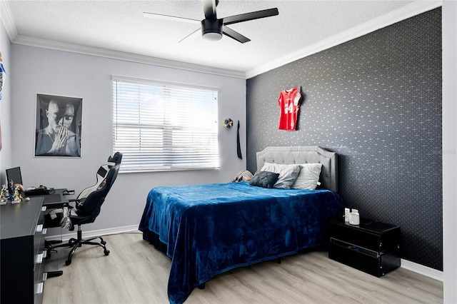 bedroom with wallpapered walls, an accent wall, crown molding, and wood finished floors