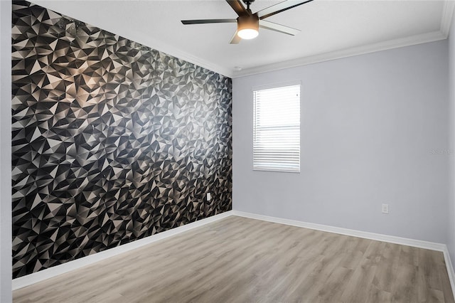 empty room featuring ornamental molding, an accent wall, wood finished floors, baseboards, and wallpapered walls