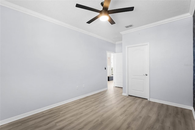 unfurnished bedroom featuring baseboards, visible vents, wood finished floors, and ornamental molding