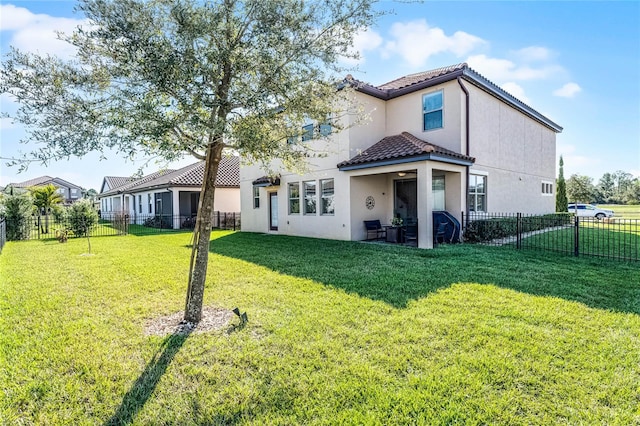 back of property featuring a tile roof, a fenced backyard, a lawn, and stucco siding