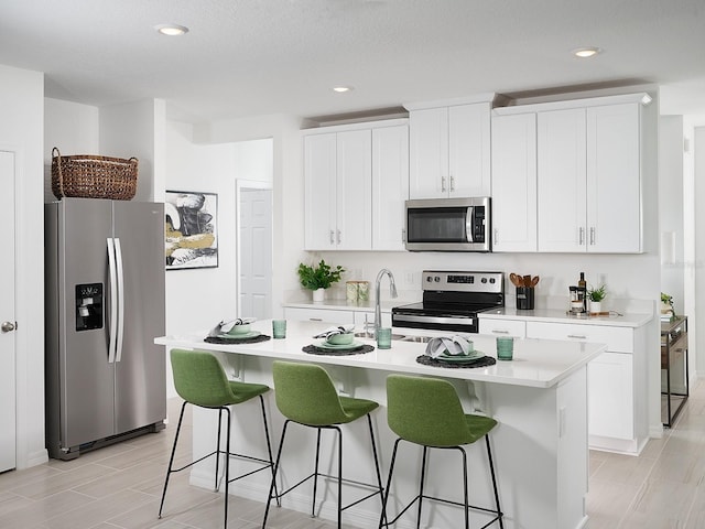 kitchen featuring light countertops, a kitchen breakfast bar, a kitchen island with sink, and stainless steel appliances