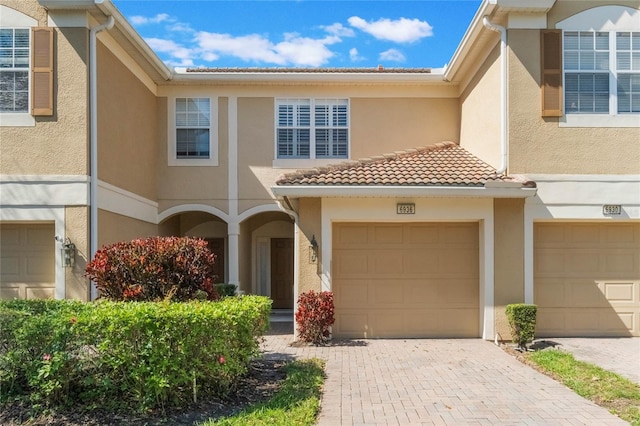 view of front of home with a garage, a tile roof, decorative driveway, and stucco siding