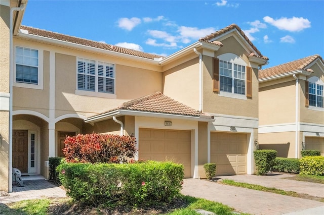 townhome / multi-family property featuring driveway, a tile roof, and stucco siding