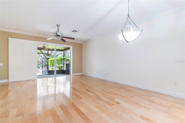 empty room with ornamental molding, visible vents, and light wood finished floors