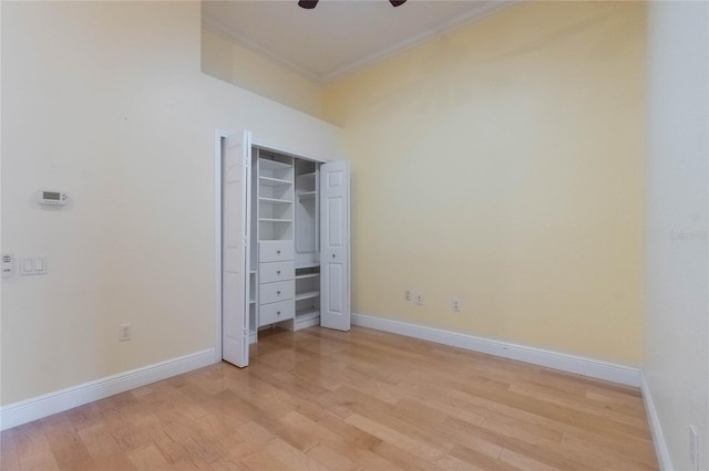 unfurnished bedroom with baseboards, light wood-style flooring, ceiling fan, crown molding, and a closet