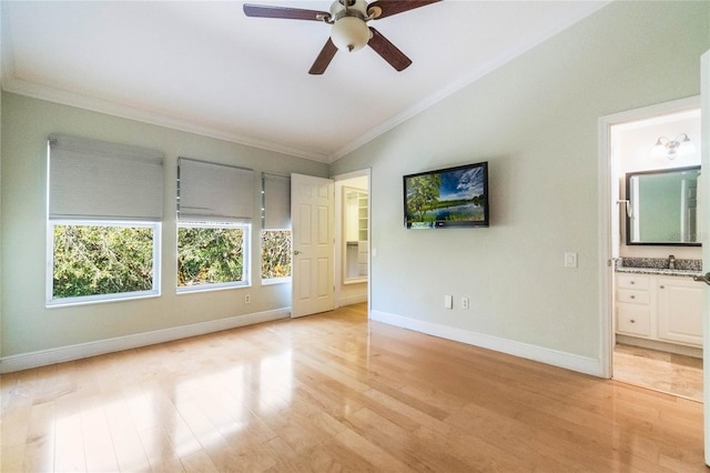 spare room with light wood-type flooring, crown molding, lofted ceiling, and baseboards