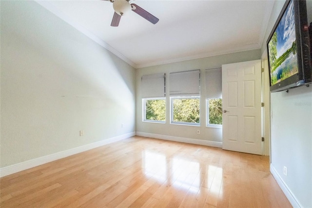 spare room with crown molding, light wood-style flooring, baseboards, and ceiling fan