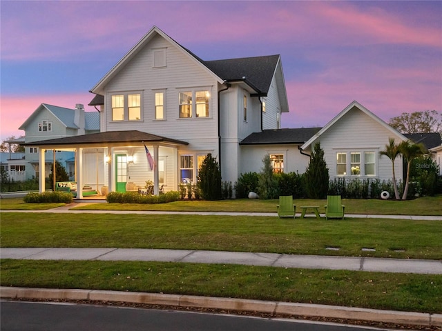 view of front of property featuring covered porch and a yard