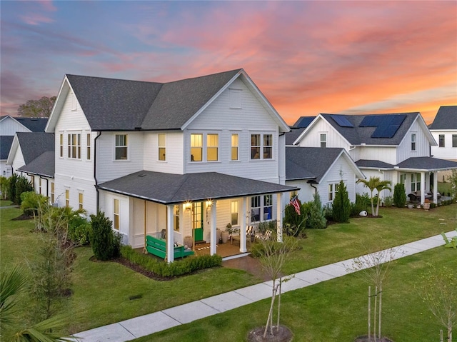 modern inspired farmhouse featuring a shingled roof, a residential view, covered porch, and a front lawn