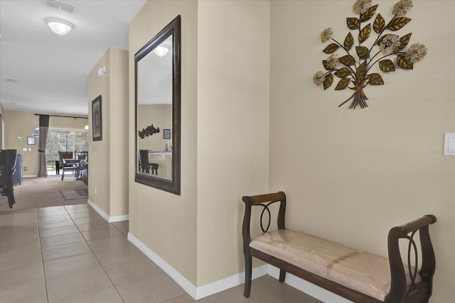 hallway featuring light tile patterned floors, baseboards, and visible vents