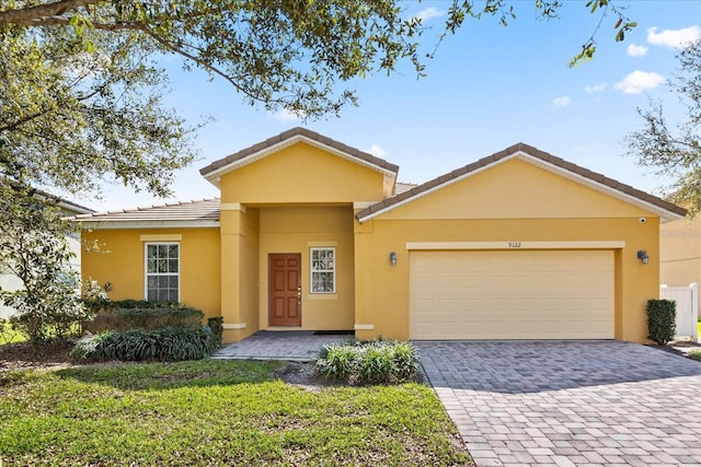 ranch-style house featuring stucco siding, a tiled roof, an attached garage, and driveway