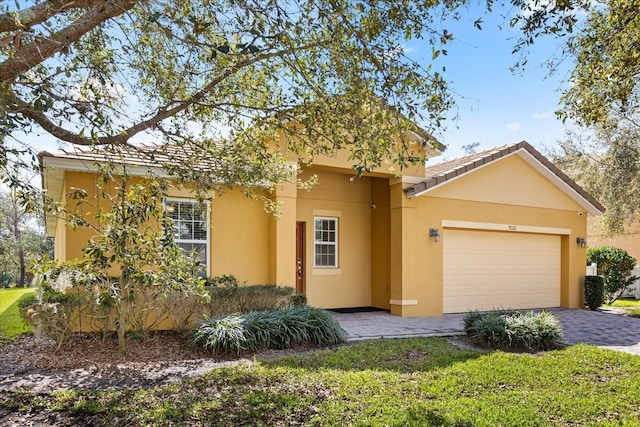 view of front of home with a tiled roof, decorative driveway, a garage, and stucco siding