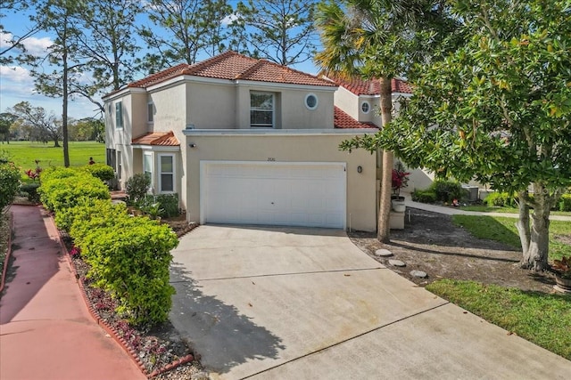 mediterranean / spanish home with concrete driveway, a tiled roof, an attached garage, and stucco siding