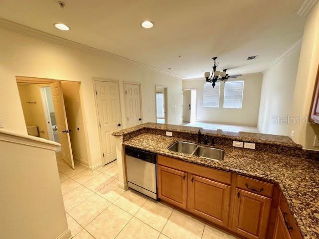 kitchen featuring a sink, ornamental molding, brown cabinets, and stainless steel dishwasher