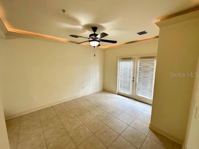 tiled empty room featuring ceiling fan, visible vents, baseboards, and french doors