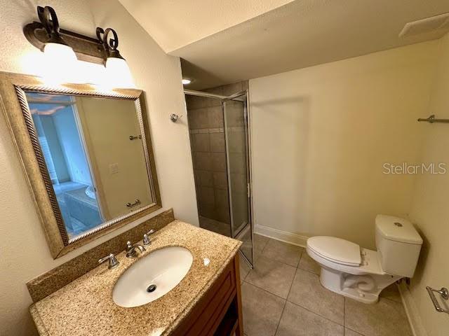 full bathroom featuring toilet, an enclosed shower, vanity, baseboards, and tile patterned floors