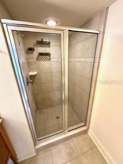 full bathroom with baseboards, a stall shower, and tile patterned floors