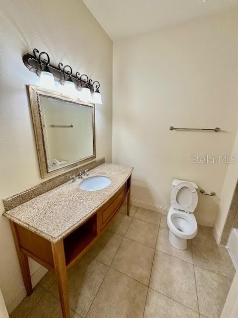 bathroom with tile patterned flooring, toilet, vanity, and baseboards