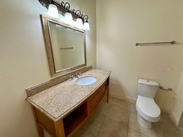 bathroom featuring tile patterned flooring, baseboards, vanity, and toilet