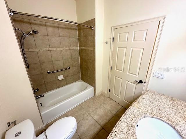 full bath with toilet, shower / washtub combination, a sink, and tile patterned floors