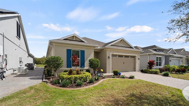 ranch-style house with central AC unit, stucco siding, an attached garage, decorative driveway, and a front yard