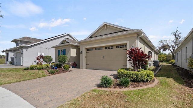 single story home with decorative driveway, stucco siding, an attached garage, central AC unit, and a front yard