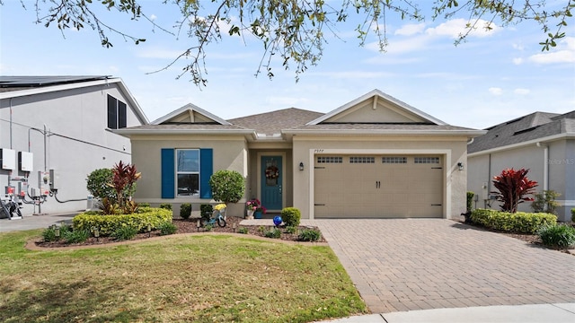 single story home with an attached garage, a front lawn, decorative driveway, and stucco siding