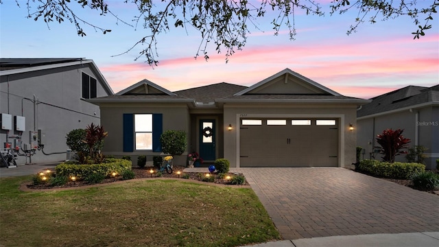 view of front facade featuring an attached garage, a front lawn, decorative driveway, and stucco siding