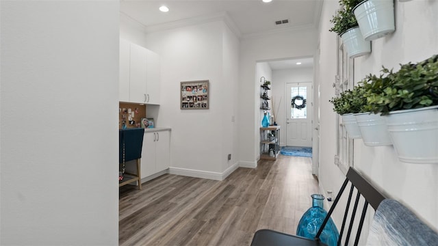 interior space with baseboards, visible vents, ornamental molding, light wood-type flooring, and recessed lighting