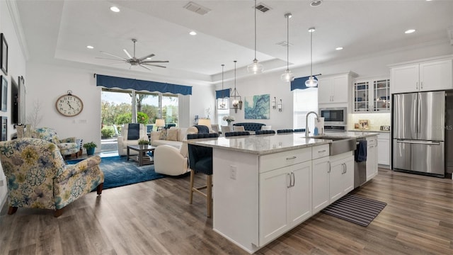 kitchen with visible vents, a raised ceiling, open floor plan, a breakfast bar, and stainless steel appliances