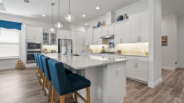 kitchen featuring appliances with stainless steel finishes, a sink, under cabinet range hood, white cabinetry, and backsplash