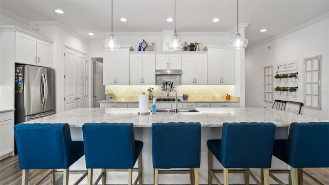 kitchen featuring a sink, white cabinetry, backsplash, freestanding refrigerator, and crown molding