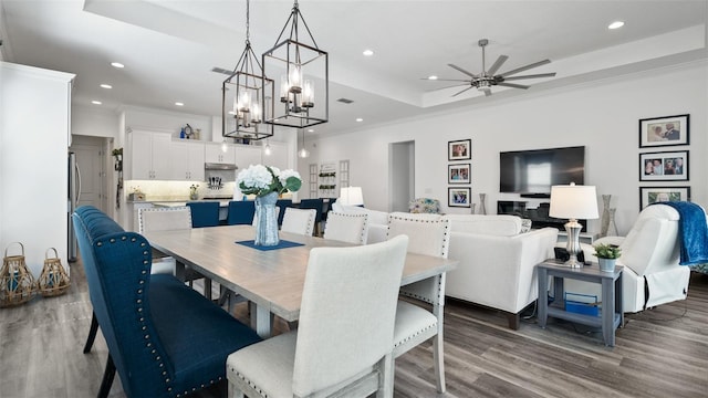 dining area featuring ornamental molding, a tray ceiling, wood finished floors, and recessed lighting