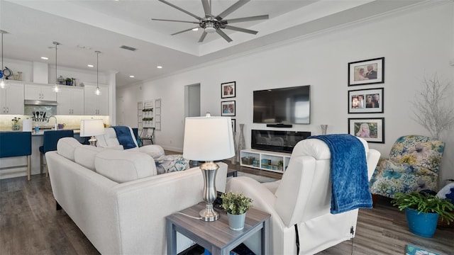 living room featuring visible vents, dark wood finished floors, crown molding, and a raised ceiling