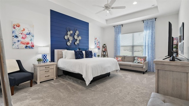 bedroom featuring a ceiling fan, a tray ceiling, and light carpet