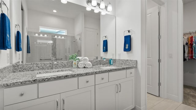 bathroom with double vanity, a spacious closet, a sink, and a shower stall