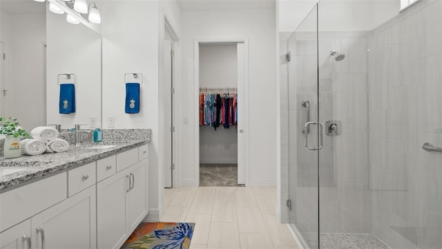 bathroom with a spacious closet, a shower stall, vanity, and baseboards