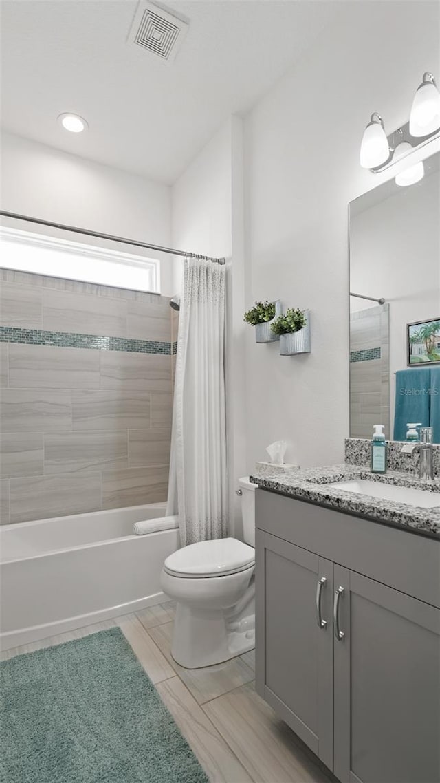 bathroom with toilet, visible vents, shower / bath combo with shower curtain, and vanity