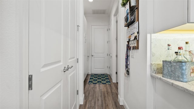 hall featuring dark wood-style flooring, visible vents, and crown molding