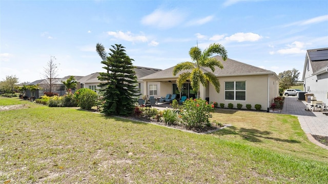 back of property with ceiling fan, a lawn, a patio area, and stucco siding