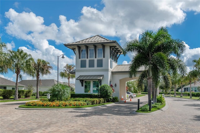 view of front of property with a standing seam roof, metal roof, decorative driveway, and stucco siding